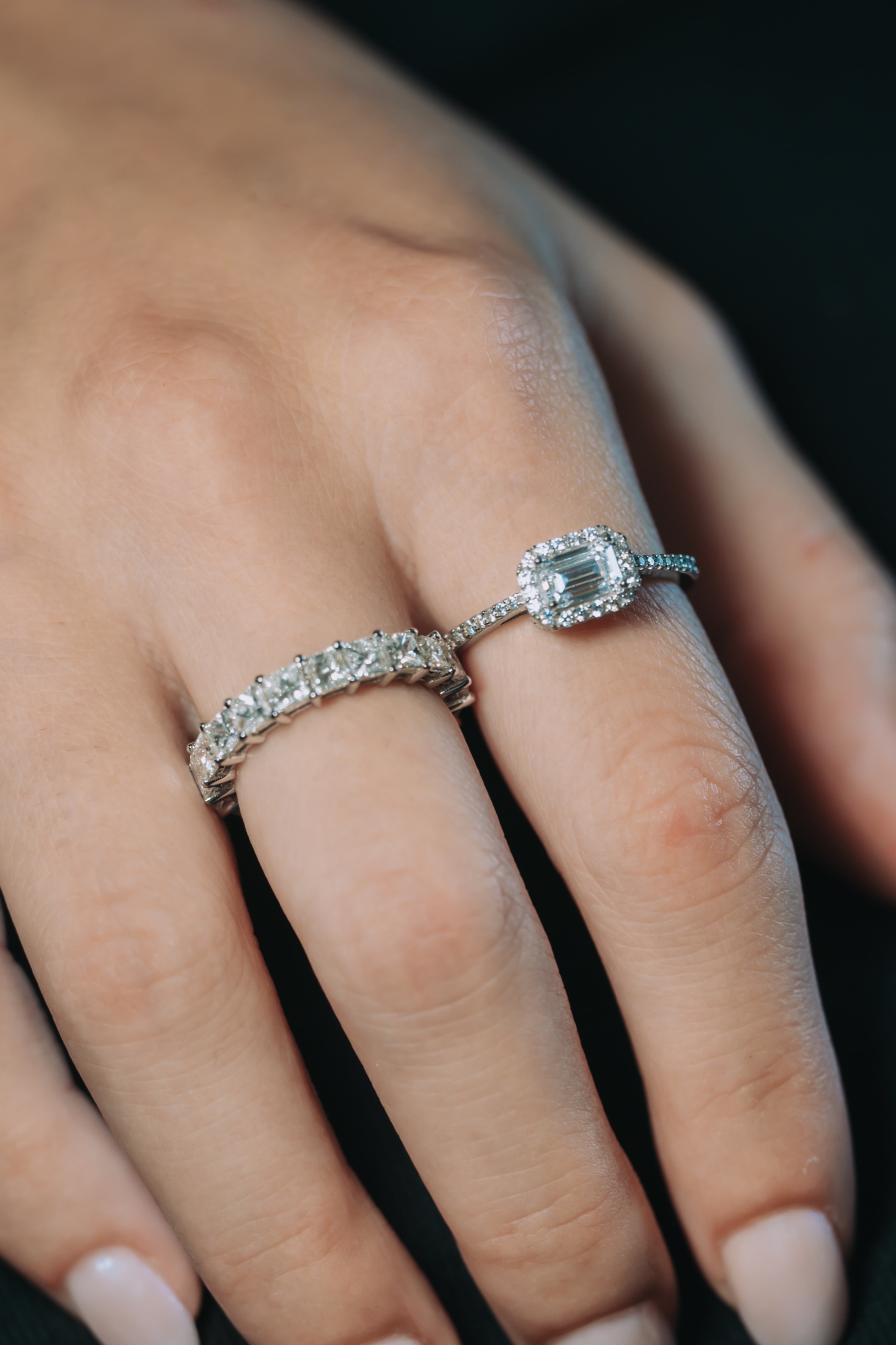 Two silver-toned rings with clear stones on a hand